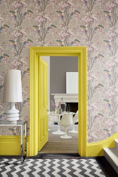 an open door leading to a living room with yellow walls and white furniture in the background