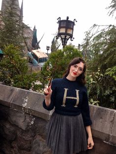 a woman is standing on a bridge with her hand up in the air and holding an umbrella