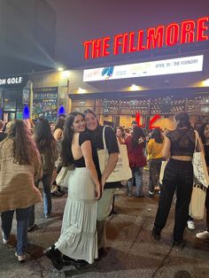 two women standing in front of a movie theater at night with the words the filmmore above them