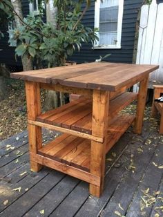 a wooden table sitting on top of a wooden deck next to a tree in front of a house