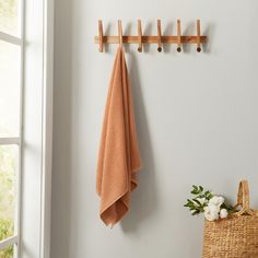 a towel hanging on the wall next to a basket with flowers and an orange towel