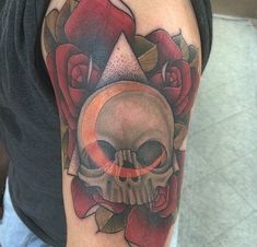 a man with a skull and roses tattoo on his arm