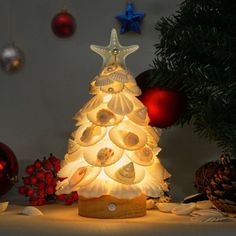 a christmas tree made out of seashells on a table with ornaments around it