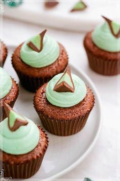 chocolate cupcakes with green frosting and a star on top are sitting on a white plate