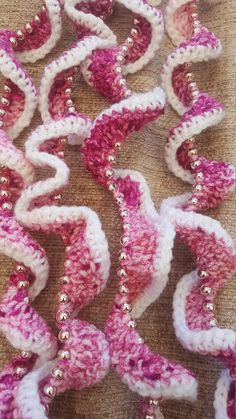 crocheted pink and white beads are laying on the tablecloth, next to each other