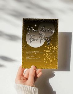 someone holding up a new year's eve party card with fireworks in the background