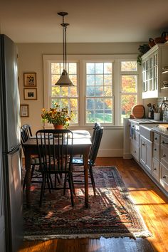 Cozy fall kitchen with large windows, framed wall art, vibrant autumnal leaves outside, and a warm dining table centerpiece. Perfect for autumn decor inspiration. Americana House Aesthetic, French Country Victorian, Mid Century Modern English Cottage, Small Dining Room In Kitchen, Townhouse Home Decor, 1890 Home Interiors, Traditionalism Aesthetic, All Creatures Great And Small Kitchen, Fall Decorations For Kitchen