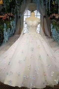 a wedding dress on display in front of flowers