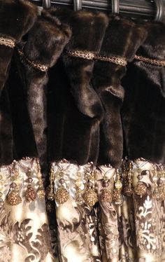 some furs are hanging on a rack in a room with gold and silver curtains