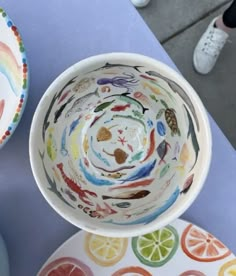 two bowls with different designs on them sitting next to each other, one has an orange slice in it