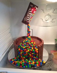 a chocolate cake with sprinkles and candy on top in an open refrigerator