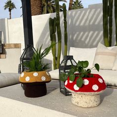 two crocheted baskets with plants in them sitting on a patio table next to a couch