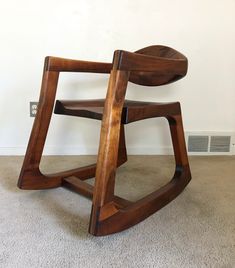 a wooden chair sitting on top of a carpeted floor next to a white wall