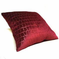 a red pillow sitting on top of a white bed