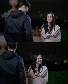 a man and woman standing next to each other in front of a building at night