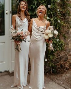 two beautiful women standing next to each other holding bouquets and smiling at the camera