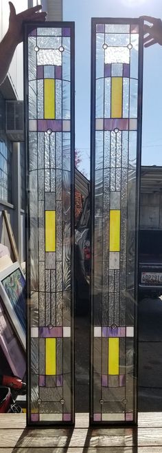 two stained glass panels sitting on top of a wooden table next to a car parked in the street