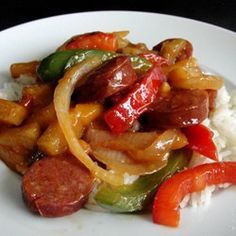 a white plate topped with rice covered in sausage and peppers