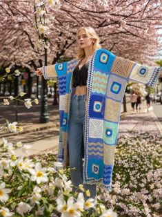 a woman is standing in the grass with her arms out and wearing a colorful blanket