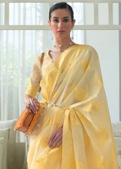 a woman wearing a yellow sari and holding a purse