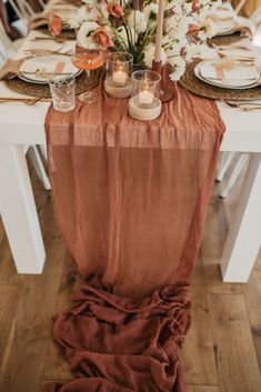 the table is set with candles, plates and flowers in vases on top of it