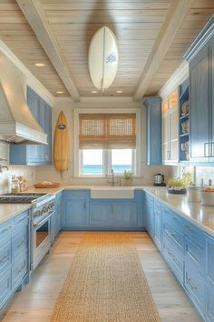 a large kitchen with blue cabinets and white counter tops, along with a surfboard mounted on the wall