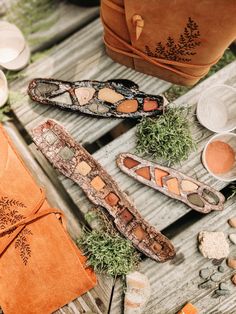 three pieces of leather sitting on top of a wooden table next to some rocks and spices