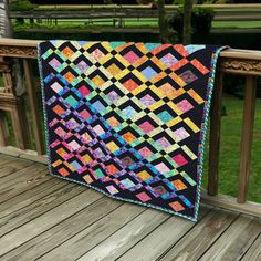 a colorful quilt sitting on top of a wooden deck