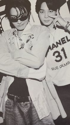 two young men standing next to each other in front of a black and white wall