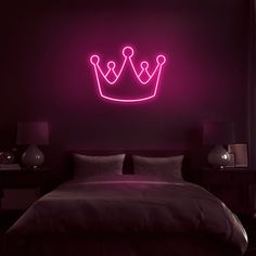 a bed with a neon crown on the wall above it