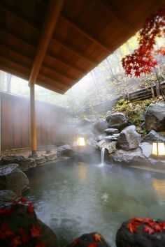 an outdoor hot tub surrounded by rocks and trees