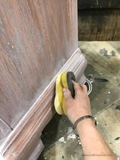 a person with a sponge on the floor next to a wooden door and a duster