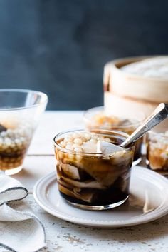 there is a dessert with ice cream and nuts in it on the plate next to two glasses