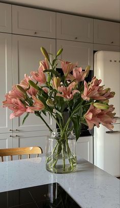 a vase filled with pink flowers sitting on top of a kitchen counter next to an oven