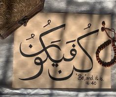 an arabic calligraphy is displayed on a piece of paper with a beaded bracelet