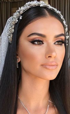 a woman with long hair wearing a veil and tiara, looking at the camera