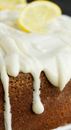 a close up of a cake on a plate with icing and lemon wedges