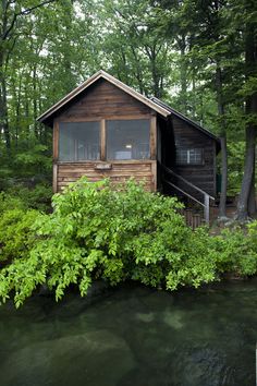 a small cabin in the woods next to a river