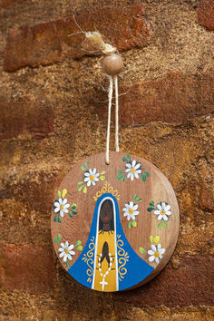 a wooden decoration hanging from the side of a brick wall with flowers and a bird on it