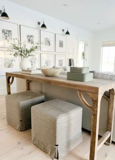 a wooden table sitting in the middle of a living room with pictures on the wall