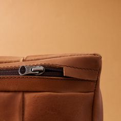 a close up view of a brown leather chair with zippers on it's side