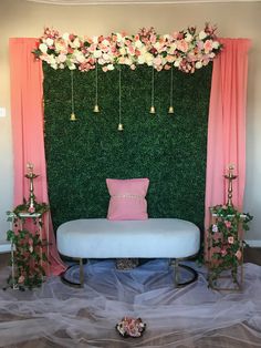 a white bench sitting in front of a green wall with pink curtains and flowers on it