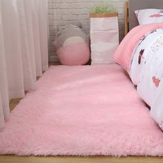 a bedroom with pink carpet and bedding on the floor next to a brick wall