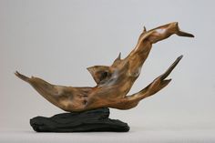 a wooden sculpture with two birds on top of it's back legs and feet