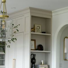 a white book shelf with books and vases on it