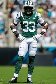 a football player is standing on the field with his hands in his pockets while wearing a green and white uniform