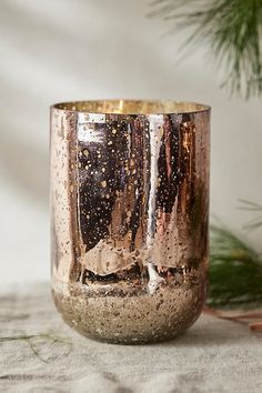 a close up of a cup on a table near a pine tree and other decorations