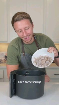 a man in an apron holding a white bowl with food inside it and the words take some shrimp