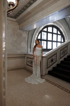 a woman in a white dress is standing on the stairs