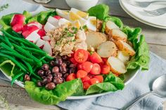 a white plate topped with lettuce, tomatoes, black beans and other vegetables